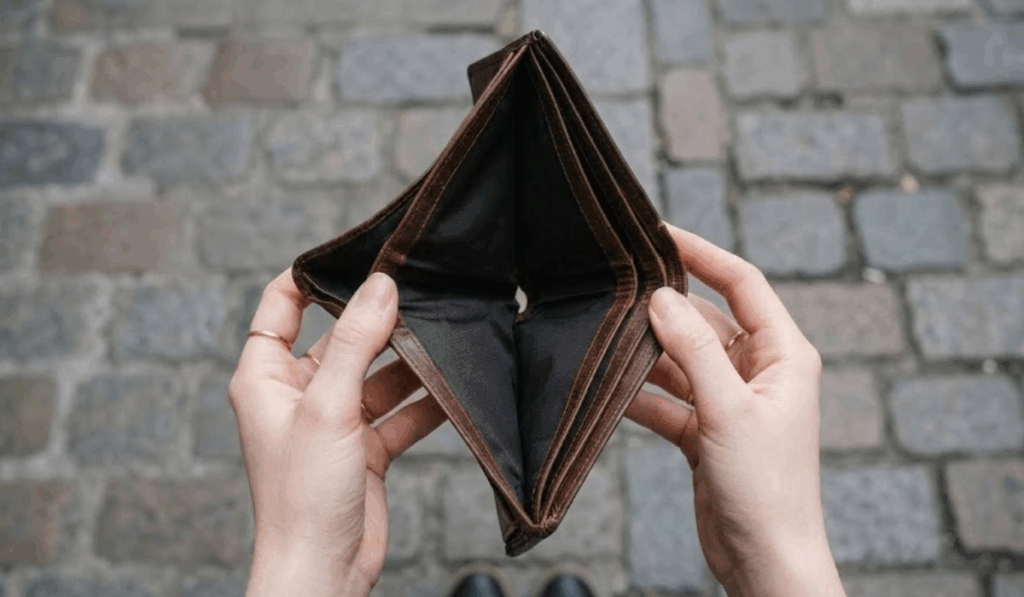 Cartera vacía en manos de una persona representando los gastos ocultos y el coste económico de mantener equipos antiguos en una oficina.